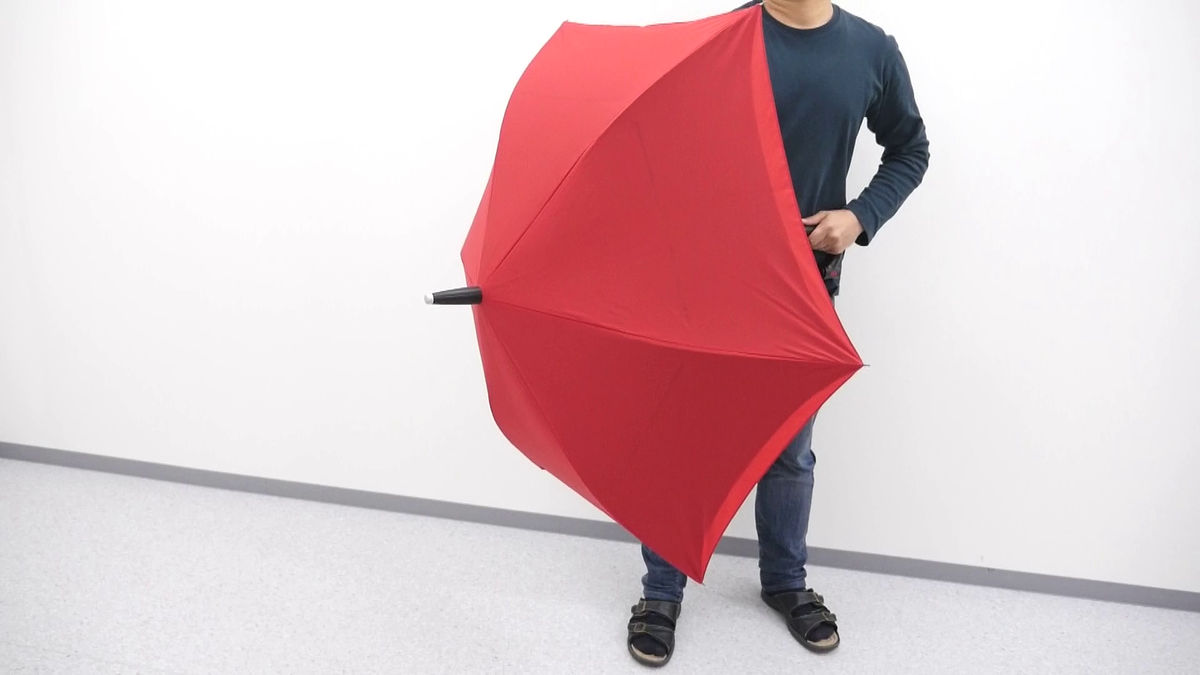 普通の傘とは真逆の動きを見せる「逆にひらく傘 GAX UMBRELLA」を使っ 
